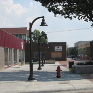 A K829 Aurora Sr. Fixture accompanied by a Sweep style arm on top of a Canterbury Jr. metal pole.