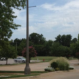 Light fixture accompanied by banner arms and a scroll style arm all on a Centennial pole.