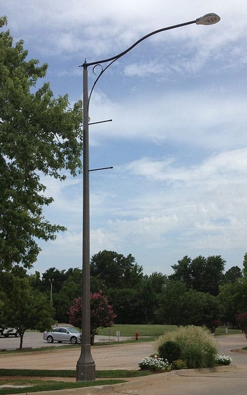 Light fixture accompanied by banner arms and a scroll style arm all on a Centennial pole.