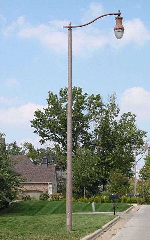 A K804 Coronet Sr. fixture accompanied by a pipe style arm on top of a Round Tapered pole.