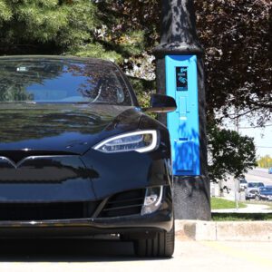 A black car utilizing some of the features offered by the VoltLock EV Charger pole.
