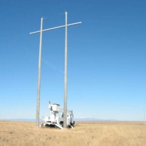 A spun concrete utility pole with an 'H Structure' application. This project is in a flat, farmland area with mountains in the background.