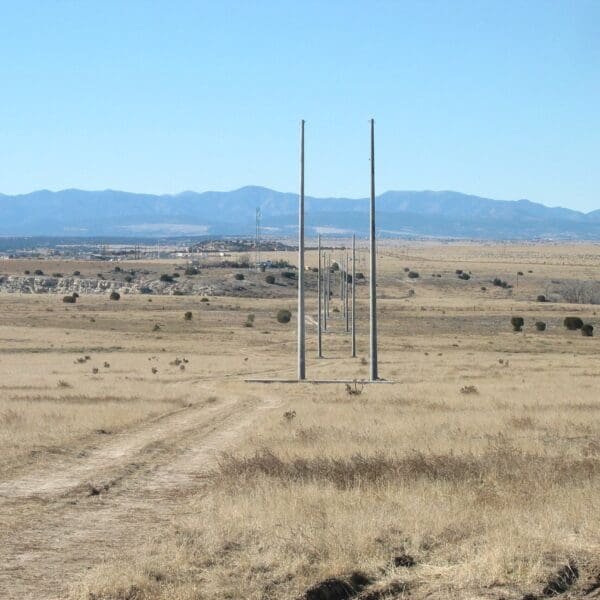 Spun concrete utility poles with a 'tangent' application. This project is in a flat, remote area with mountains in the background.