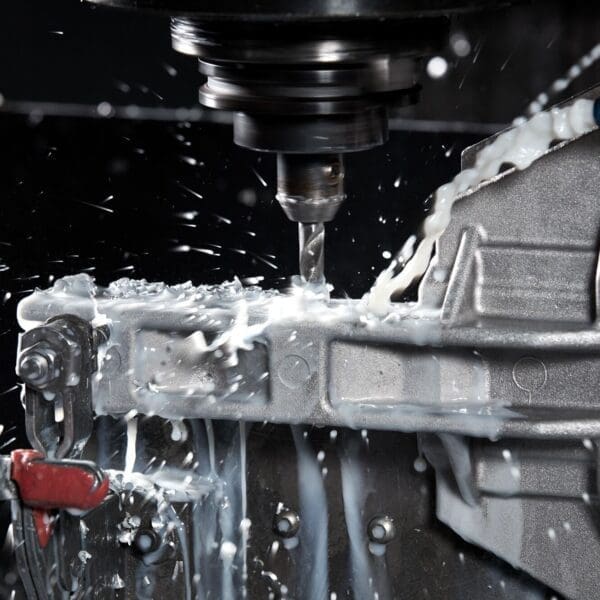 An employee at King Cast using tools from our manual machine shop to drill a hole into a piece of metal.