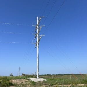 Utility Pole - Angle A spun concrete utility pole with an 'angle' application. This project is in a flat, grassy area.