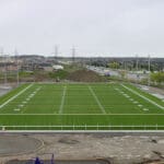 Multiple Spartan sports lighting poles overlooking a soccer field.