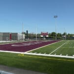 Multiple Spartan sports lighting poles overlooking a football field.